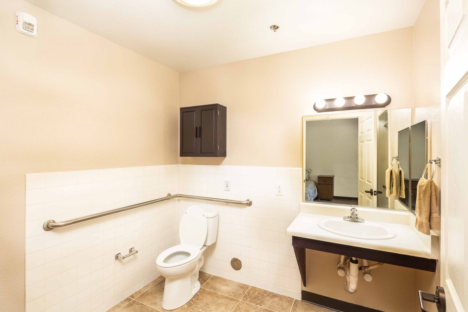Bathroom with toilet, sink, wall cabinet and grab bars.