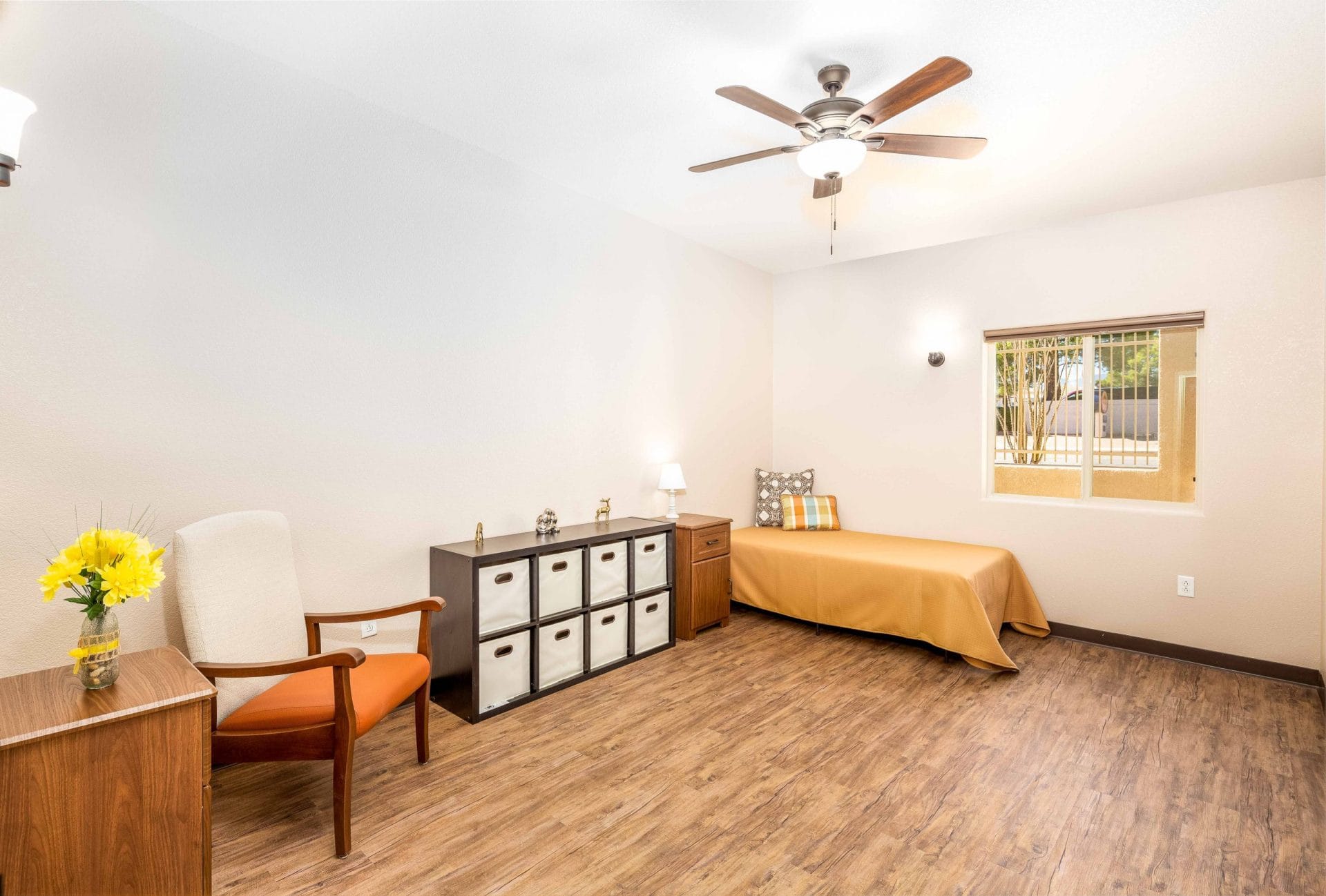 Bedroom with gold bedding, a ceiling fan and storage cubes.